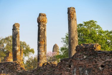 Tarihi bölgede, Budist pagoda ile birlikte antik duvarlar ve sütunlar günbatımının ışığında berrak mavi gökyüzü ile ağaçların arasında duruyordu..
