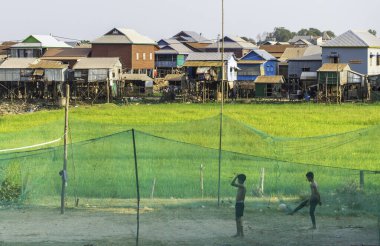 Kamboçya-21 Şubat 2024: Phnom Krom tapınağının altındaki köyde, aralarında pirinç tarlası bulunan gençler, Siem Reap şehrinin birkaç kilometre güneyinde top oynuyorlar..