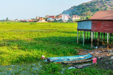 Phnom Krom tepesine ve aşağıdaki köye doğru bakan, öğleden sonra yükselen duman ve arasında bataklık alanı kaplayan canlı yeşil yapraklı bitkiler.
