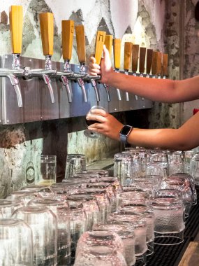 Barmen bira musluklarından bira ve bira dökerken, gece vakti küçük anonim bir barda çeşitli bira fıçıları satıyorum..