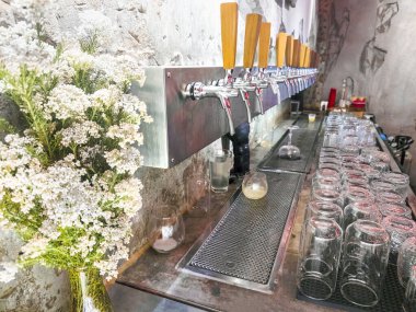 Küçük isimsiz bir barda gece çeşitli bira satışı, bir sürü bira musluğu ve sıralanmış sıralı temiz bardaklar, düzenli ve kullanıma hazır..