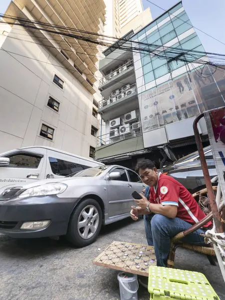 Tayland-Nisan 07 2024-Araba park görevlileri 88 katlı yapının altında, mavi gökyüzüne ve yukarıdaki güneş ışığına bakan gölgede oturuyorlar..