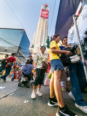 Tayland-Nisan 07-2024 Birçok insan, Baiyoke Gökyüzü Oteli 'nin güneş ışığının ötesine yükselmesiyle öğleden sonra açık bir pazarda mal satın alıyor..