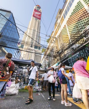 Tayland-Nisan 07-2024 Birçok insan, Baiyoke Gökyüzü Oteli 'nin güneş ışığının ötesine yükselmesiyle öğleden sonra açık bir pazarda mal satın alıyor..