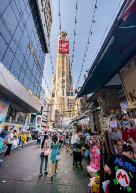 Tayland-Nisan 07-2024 Birçok insan, Baiyoke Gökyüzü Oteli 'nin güneş ışığının ötesine yükselmesiyle öğleden sonra açık bir pazarda mal satın alıyor..