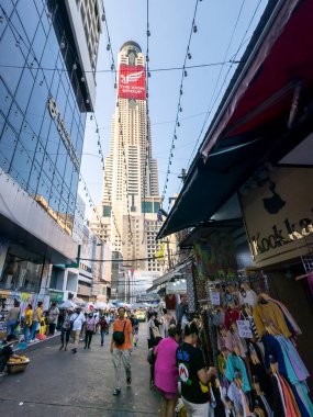 Tayland-Nisan 07-2024 Birçok insan, Baiyoke Gökyüzü Oteli 'nin güneş ışığının ötesine yükselmesiyle öğleden sonra açık bir pazarda mal satın alıyor..