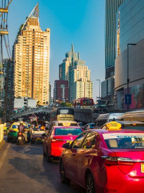 Bangkok, Tayland-07 Nisan 2024 öğleden sonra, alçak açılı güneş ışığı yoğun saatlerde yukarıdaki binalara ve aşağıdaki yoğun trafiğe rastgele yansıyor.