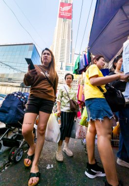 Tayland-Nisan 07-2024 Birçok insan, Baiyoke Gökyüzü Oteli 'nin güneş ışığının ötesine yükselmesiyle öğleden sonra açık bir pazarda mal satın alıyor..