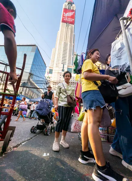 Tayland-Nisan 07-2024 Birçok insan, Baiyoke Gökyüzü Oteli 'nin güneş ışığının ötesine yükselmesiyle öğleden sonra açık bir pazarda mal satın alıyor..