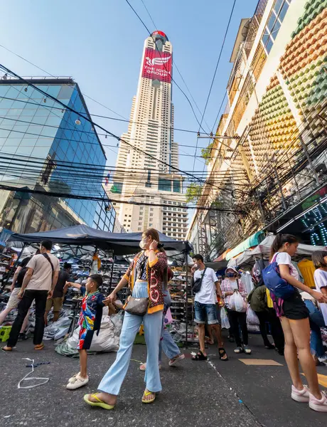 Tayland-Nisan 07-2024 Birçok insan, Baiyoke Gökyüzü Oteli 'nin güneş ışığının ötesine yükselmesiyle öğleden sonra açık bir pazarda mal satın alıyor..
