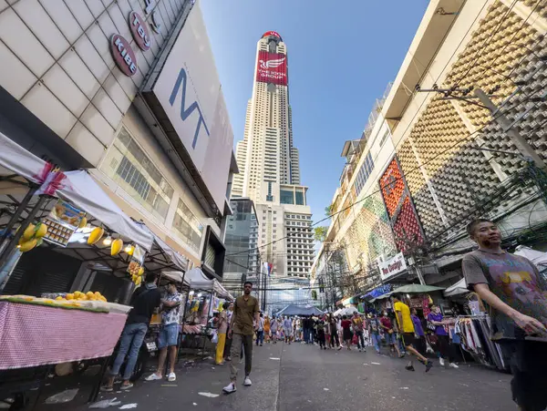 Tayland-Nisan 07-2024 Birçok insan, Baiyoke Gökyüzü Oteli 'nin güneş ışığının ötesine yükselmesiyle öğleden sonra açık bir pazarda mal satın alıyor..
