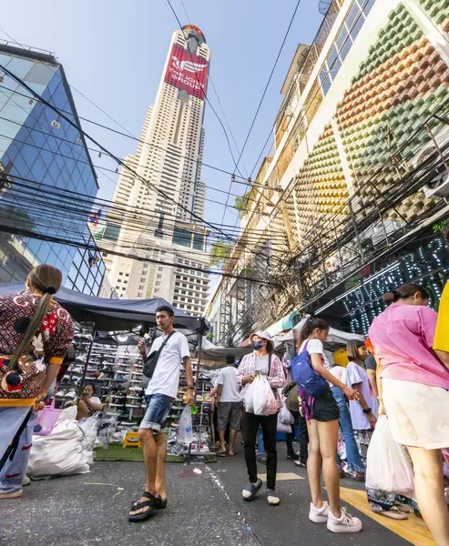 Tayland-Nisan 07-2024 Birçok insan, Baiyoke Gökyüzü Oteli 'nin güneş ışığının ötesine yükselmesiyle öğleden sonra açık bir pazarda mal satın alıyor..