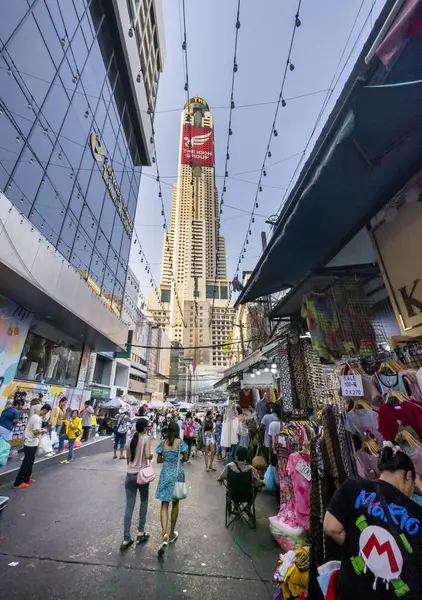Tayland-Nisan 07-2024 Birçok insan, Baiyoke Gökyüzü Oteli 'nin güneş ışığının ötesine yükselmesiyle öğleden sonra açık bir pazarda mal satın alıyor..