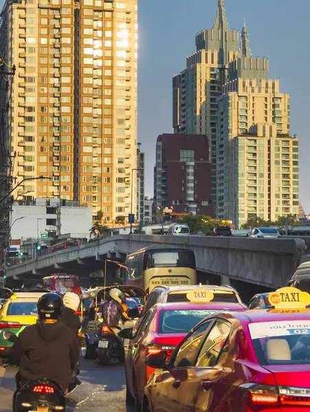 Bangkok, Tayland-07 Nisan 2024 öğleden sonra, alçak açılı güneş ışığı yoğun saatlerde yukarıdaki binalara ve aşağıdaki yoğun trafiğe rastgele yansıyor.