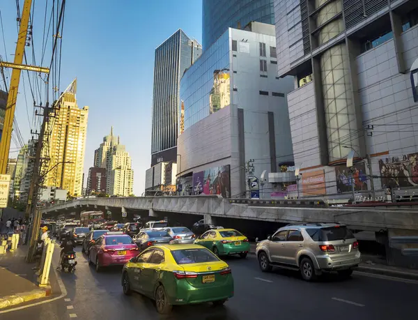 Bangkok, Tayland-07 Nisan 2024 öğleden sonra, alçak açılı güneş ışığı yoğun saatlerde yukarıdaki binalara ve aşağıdaki yoğun trafiğe rastgele yansıyor.