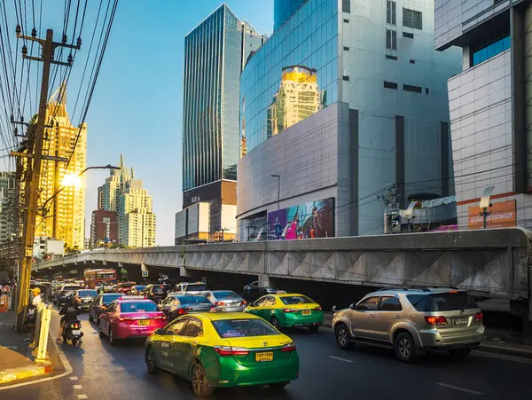 Bangkok, Tayland-07 Nisan 2024 öğleden sonra, alçak açılı güneş ışığı yoğun saatlerde yukarıdaki binalara ve aşağıdaki yoğun trafiğe rastgele yansıyor.