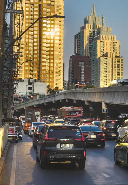 Bangkok, Tayland-07 Nisan 2024 öğleden sonra, alçak açılı güneş ışığı yoğun saatlerde yukarıdaki binalara ve aşağıdaki yoğun trafiğe rastgele yansıyor.