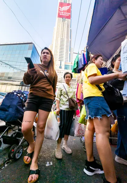 Tayland-Nisan 07-2024 Birçok insan, Baiyoke Gökyüzü Oteli 'nin güneş ışığının ötesine yükselmesiyle öğleden sonra açık bir pazarda mal satın alıyor..