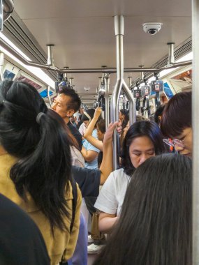 Bangkok, Tayland-30 Haziran 2024: Bir BTS Skytrain vagonunda, şehir merkezine doğru bir yolculukta, öğleden sonra, yolcular nispeten daha rahat bir şekilde seyahat ederler..