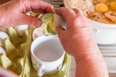 İyi burjuva ev kadını mutfakta yemek pişirir. Yumurta çırpar ve yumurta sarısını bardakla beyazdan ayırır. Ekmek kırıntılarıyla ekmek köftesi yapmak için.