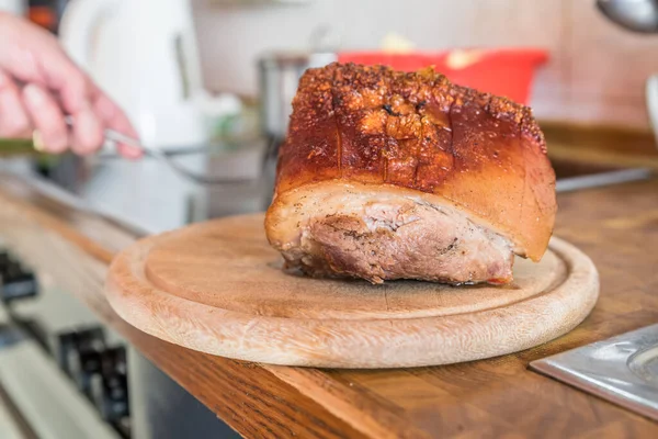 stock image Real hearty homemade roast pork is cut into portions on a wooden board in the kitchen, Germany