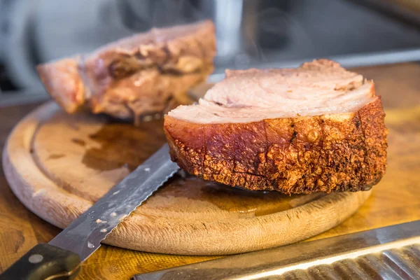 stock image Real hearty homemade roast pork is cut into portions on a wooden board in the kitchen, Germany