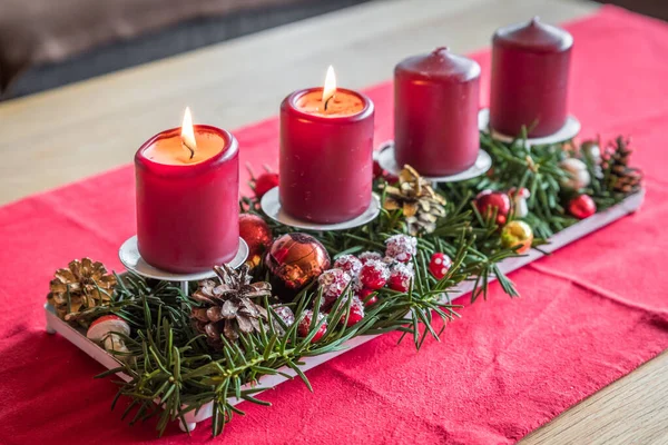 圣诞前夕 在客厅的一张木制桌子上 用红色布布点着红色的蜡烛和装饰品 免版税图库图片
