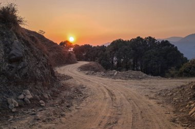 Kış günbatımının dingin güzelliğini tecrübe edin. Altından parıltısını asfaltsız bir köy yoluna saçın..
