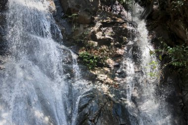 Küçük ağaçların büyüdüğü taş duvarlardan oluşan serinletici şelaleyi kapat.