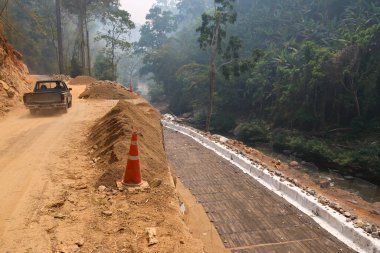 İnşaat halindeki kırsal yollar demir ve çimento bariyerleri oluşturuyor. Yağmur mevsiminde yollar kesilir ve toprak kayar. Ormandaki nehir vadisi yolu