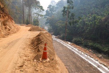 İnşaat halindeki kırsal yollar demir ve çimento bariyerleri oluşturuyor. Yağmur mevsiminde yollar kesilir ve toprak kayar. Ormandaki nehir vadisi yolu