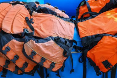 Mavi bir tekneye dizilmiş kaliteli turuncu can yelekleri. Su faaliyetleri için güvenlik ekipmanları: Rafting müşterileri için can yelekleri mevcuttur.