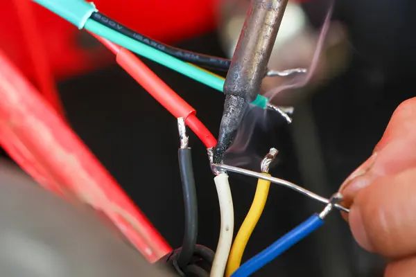 selective focus wires in the hand of a car mechanic Practicing repairs to the ATV\'s electrical system. Wires of various colors help you know the direction of your car\'s electrical system.