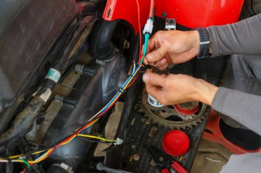 ATV 'nin elektrik sistemini tamir etmeye çalışan bir araba tamircisinin elindeki seçici odaklanma kabloları. Çeşitli renklerdeki kablolar arabanızın elektrik sisteminin yönünü bilmenize yardımcı olur..
