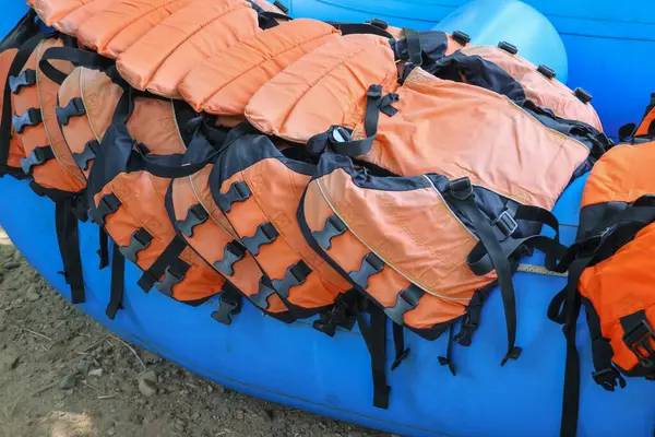 Good quality orange life jackets lined up on a blue boat. Safety equipment for water activities: Life jackets are available for rafting customers.