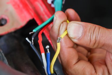 ATV 'nin elektrik sistemini tamir etmeye çalışan bir araba tamircisinin elindeki seçici odaklanma kabloları. Çeşitli renklerdeki kablolar arabanızın elektrik sisteminin yönünü bilmenize yardımcı olur..
