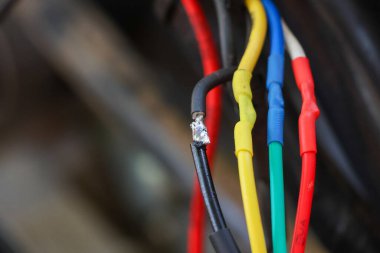 ATV 'nin elektrik sistemini tamir etmeye çalışan bir araba tamircisinin elindeki seçici odaklanma kabloları. Çeşitli renklerdeki kablolar arabanızın elektrik sisteminin yönünü bilmenize yardımcı olur..