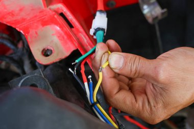 ATV 'nin elektrik sistemini tamir etmeye çalışan bir araba tamircisinin elindeki seçici odaklanma kabloları. Çeşitli renklerdeki kablolar arabanızın elektrik sisteminin yönünü bilmenize yardımcı olur..