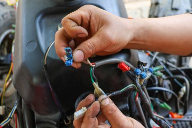 Araba tamircisinin elindeki kabloları ayırmak için seçici odaklı elektrikli köprü. Arabanın elektrik sistemi tamir ediliyor..