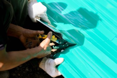 İnşaat işçisinin elindeki çinko kesme makası ısıya dayanıklı fitil ile galvanize çeliği kesiyor.