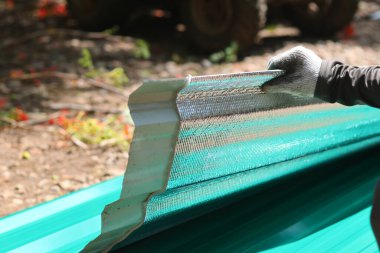 Bina malzemeleri satan bir dükkandan alınan galvanizli yeni bir çarşafa iliştirilmiş seçici odaklı ısı kalkanı. Bir araba tamirhanesinin çatısına kurulum için..