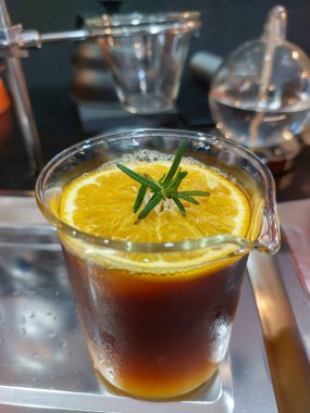 Limon suyuyla karıştırılmış kahve bardağında dilimlenmiş limon. Üstünde biberiye yaprakları var. Dükkanda limonla karıştırılmış kahve ferahlatıcıdır.