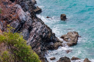 Deniz kenarındaki kayaların yüksek açılı manzarası adadaki dağdan serin esinti, yeşil ağaçlar ve mavi deniz manzarası. Tayland 'da yaz aylarında hava güzel ve ferahlatıcıdır..