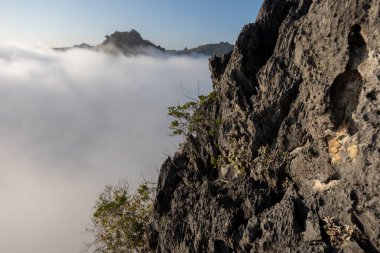seçici odak, yüksek bir kayanın tepesinde delici bulutlar, hava açık ne kadar yükseğe çıkarsanız manzara o kadar güzel olur. Metin için boşluk var.