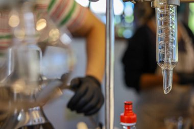 Serinletici içecek dükkanında sıvı damıtma ekipmanları için seçici odaklı cam tüp makarası satılık içecekler yapmak için bilimsel deney ekipmanları kullanın..