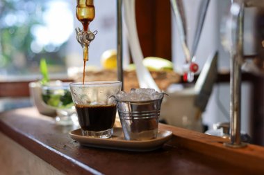 Serinletici içecek dükkanında elde edilen sıvı damıtma ekipmanından elde edilen temiz bardakta seçici odaklı sade kahve. Satılık içecekler yapmak için bilimsel deney ekipmanları kullanın..