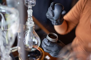 Seçici odak noktası, paslanmaz çelik bardak ve kahve çekirdekleri ile kahve dükkanı çalışanı kahve çekirdeğinin kabuklarını kurutarak damlatıyor..