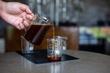 Açık bir bardakta seçici bir odak kahvesi cam sürahiden açık bir ölçüm bardağına kahve dolduruyor ve bardağın kenarındaki miktarları gösteriyor..