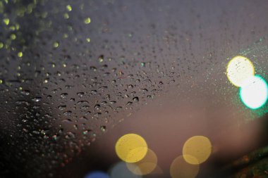 Geceleri arabanın ön camına seçici odaklı su damlaları yalnızlık hissi verir. Ve bir şey bekliyor. Metin için yer var. Şehir ışıklarından bir çakma var..