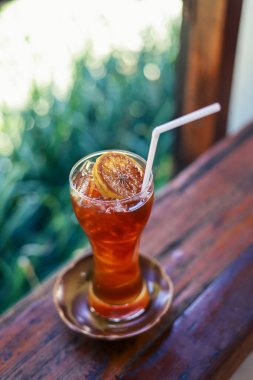 Seçici odaklı soğuk içecek Craft Cola buzla dolu güzel, berrak bir bardak ve üstüne bir dilim limon. Pencerenin dışında serinletici bir arka plan, kırsal bir kafede serin bitkisel içecekler